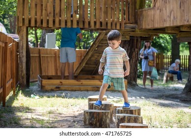 Little Boy Climbing On A Wooden Playground In A Rope Park. Kid Play Outdoors On Warm Sunny Summer Day.