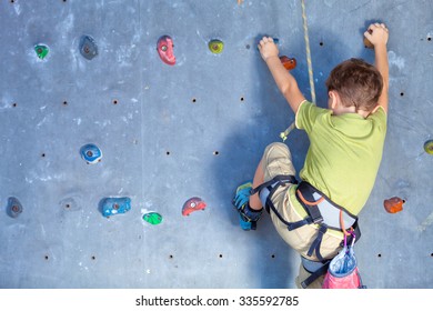 little boy climbing a rock wall indoor - Powered by Shutterstock