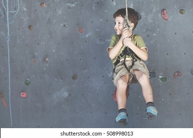 Little Boy Climbing A Rock Wall Indoor