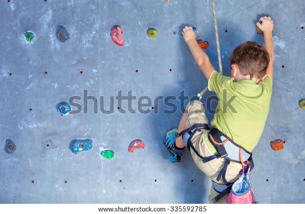 little boy climbing a\
rock wall indoor