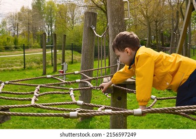 Little Boy Climbing Up Rope Net At Playground