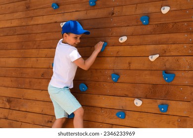 A little boy climbs a climbing wall on an eco-friendly wooden playground in Europe	 - Powered by Shutterstock