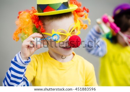 Little boy in clown costume blowing bubbles outdoors at summer day