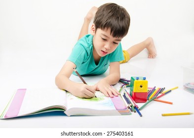Little boy coloring image lay on th floor