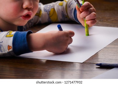 Little boy coloring on table with crayons and white sheet of paper. - Shutterstock ID 1271477932