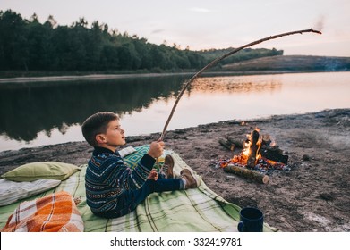 Little boy cooking a marshmallow over a campfire at night