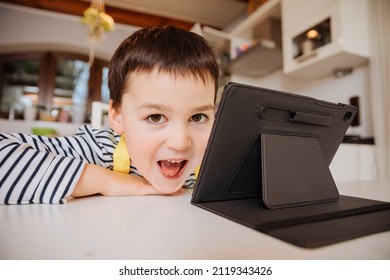 Little Boy Cooks And Looks At A Recipe On The Internet On A Tablet. Children And Media Consumption. Digitalization. Child Playing On A Tablet In The Kitchen	