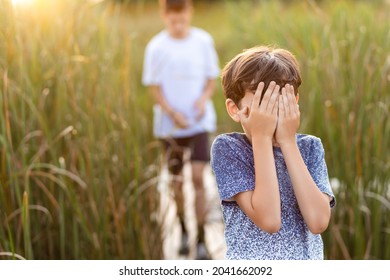 The Little Boy Covered His Face With His Hands, As If He Was Playing Hide And Seek Or Was Afraid Of Something. A Frightened Child Hides From His Parents