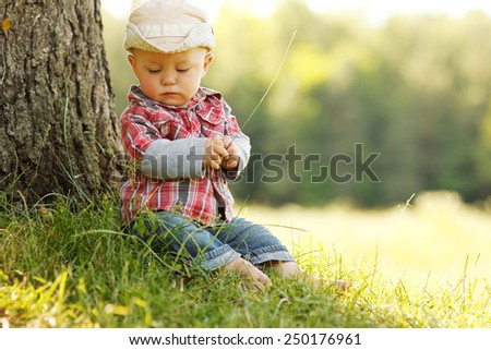 a little boy in a cowboy hat playing on nature