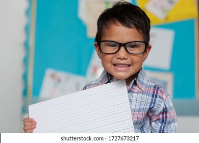 A Little Boy With A Cute Smile Who Is Holding Up A Writting Guide Board And Is Wearing Reading Glasses With A Preppy Style Shirt.