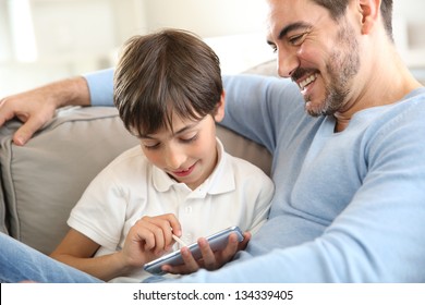 Kleiner Junge mit Papa, der mit Smartphone spielt