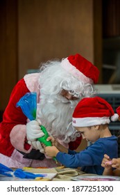 Little Boy Decorating Christmas Biscuits And Gingerbread Cookies In Kitchen Together With Santa Claus. Kids Cooking Class. Merry Christmas And Happy Holidays Concept