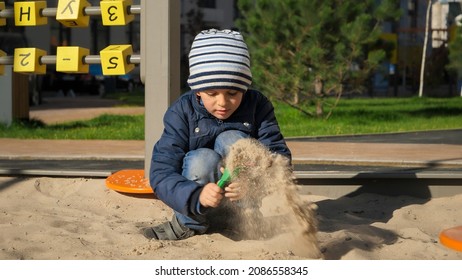 Little Boy Digging Sand In Sandpit With Shovel On Playground. Concept Of Child Development, Sports And Education.