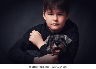 Little boy with a dog on a dark background. Studio shot. - Shutterstock ID 2381264607