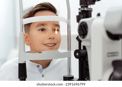 Little boy doing examination of the eyes while looking through autorefractor. Health care concept - Powered by Shutterstock