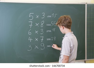 Little boy is doing some maths at a blackboard in school