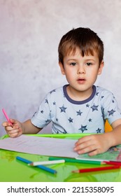 Little boy drawing and color pencils  Boy  drawing picture for fathers day  Small boy draws at the table  Little boy is holding color pencils 