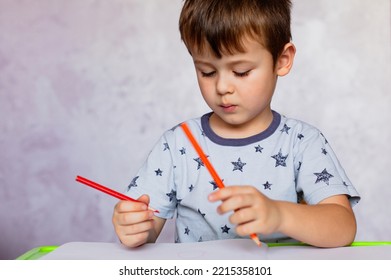 Little boy drawing and color pencils  Boy  drawing picture for fathers day  Small boy draws at the table  Little boy is holding color pencils 