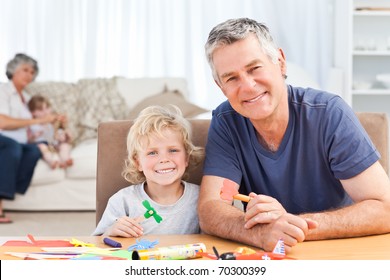 Little Boy Drawing With His Grand Father At Home