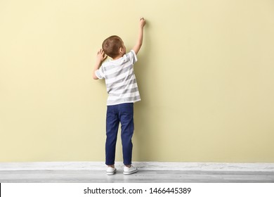 Little boy drawing on color wall