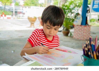 Little boy drawing picture on table outdoor;