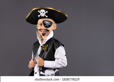 Little boy dressed as a pirate with makeup on his face is having fun at a Halloween party. Face painting for children. Isolated gray background with blank space. - Powered by Shutterstock