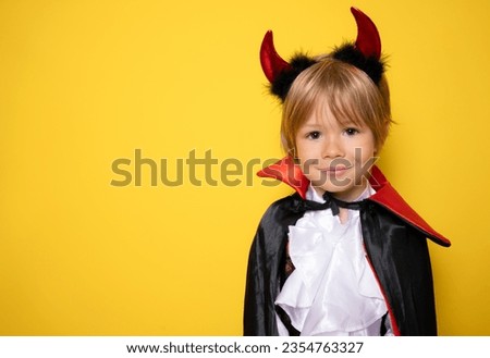 little boy dressed as a vampire on halloween isolated over yellow background. Halloween celebration concept