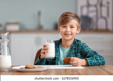 Little Boy Drinking Milk And Eating Cookies In Kitchen