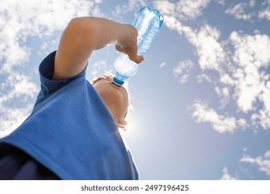 Little boy drinking water from bottle on a hot summer day, thirsty child drinks from water bottle replenish fluids in summer heat wave. 
 - Powered by Shutterstock