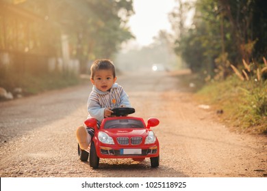 Little boy driving big toy car ,Child enjoying warm summer day in sunrise morning