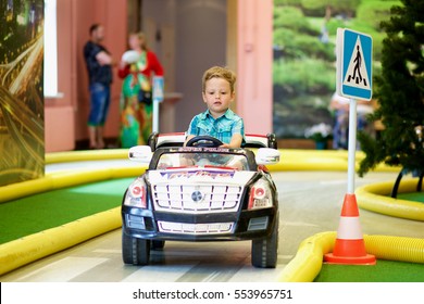 Little boy driving toy car on the traffic playground