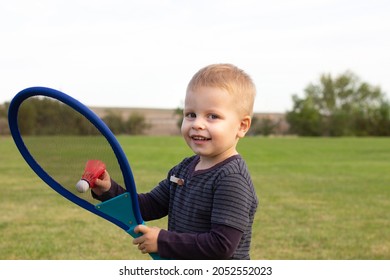 Little boy during tennis training or workout. Preschooler playing badminton in summer park. Child with small tennis racket and ball. Kid tennis player