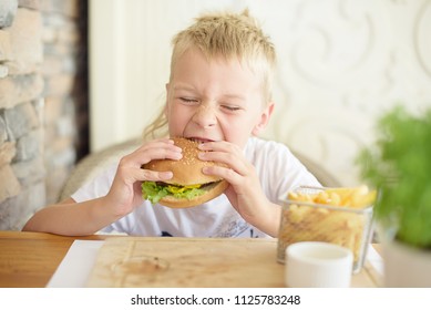 Little Boy Eating Burger In Cafe