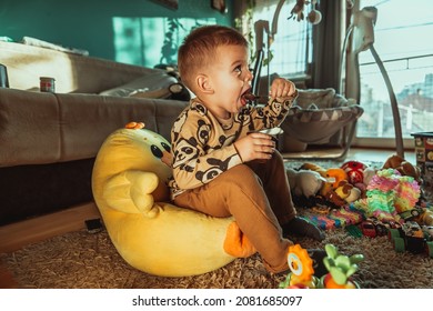 Little Boy Eating Chocolate Pudding And Watching Tv. Cute Happy Boy Smeared With Chocolate Around His Mouth. Child Concept, Home Concept