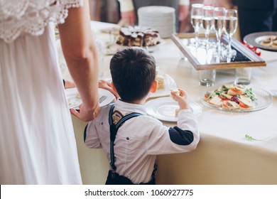 Little Boy Eating Food Appetizers On Table At Wedding Reception. Luxury Catering At Celebrations. Serving Food And Drinks At Events Concept