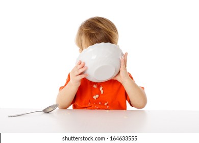 Little boy eating the oatmeal from a bowl, isolated on white
