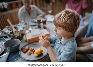 Little boy eating roasted corn and vegetables at family barbecue party in garden. - Shutterstock ID 2278261067