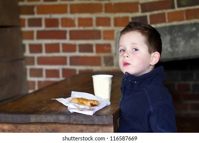 Little Boy Eating Sausage Roll And A Cup Of Coffee