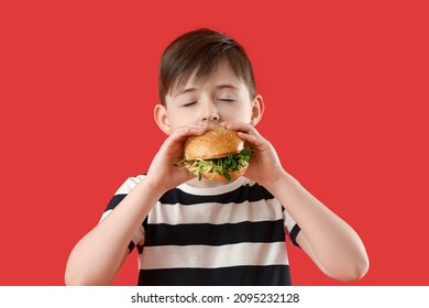 Little Boy Eating Tasty Vegan Burger On Color Background