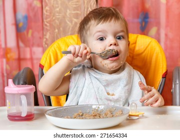 Little boy eats buckwheat cereal by himself