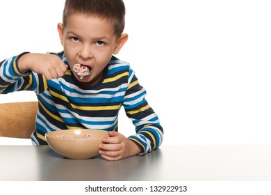 A little boy eats with a spoon his breakfast