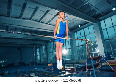 The little boy is engaged in sports gymnastics on a parallel bars at gym. The performance, sport, acrobat, acrobatic, exercise, training concept