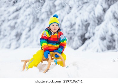 Little boy enjoying a sleigh ride. Child sledding. Toddler kid riding a sledge. Children play outdoors in snow. Kids sled in the Alps mountains in winter. Outdoor fun for family Christmas vacation. - Powered by Shutterstock