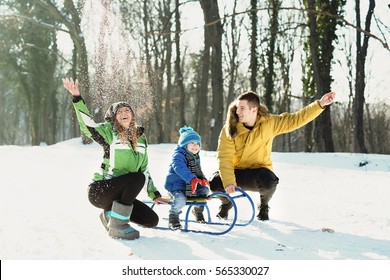 Little Boy Enjoying A Sleigh Ride. Child Sledding With Young Mom And Dad. Toddler Kid Riding A Sledge. Children Play Outdoors In Snow. Kids Sled In Winter Park. Outdoor Active Fun For Family Vacation.