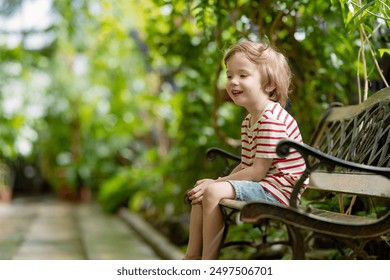 Little boy exploring different species of tropical plants and flowers in botanical garden of Tartu, Estonia. Lush exotic vegetation grown in a greenhouse. - Powered by Shutterstock