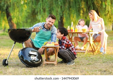 Little boy with father cooking tasty food on barbecue grill outdoors - Powered by Shutterstock