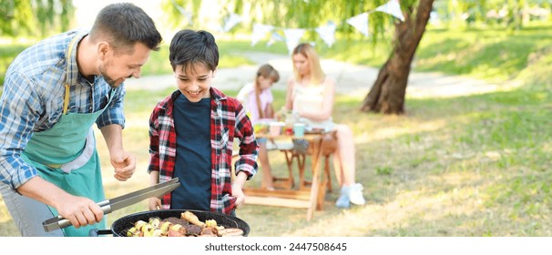 Little boy with father cooking tasty food on barbecue grill outdoors - Powered by Shutterstock