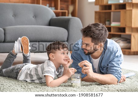 Little boy and father with savings for education at home