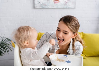 Little Boy Feeding Happy Mother While Sitting On Kids Chair