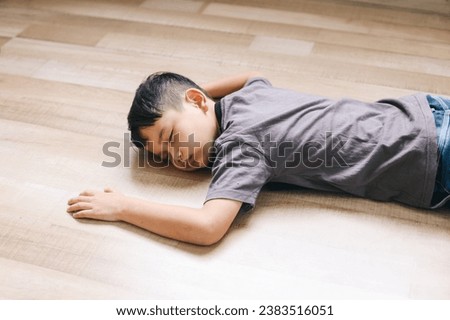 Little boy feeling tired and sleeping on wooden floor. Fainted boy. 